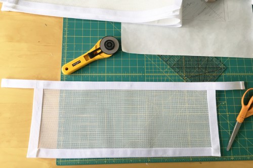 I cut white vinyl mesh the length of the shelves and about 9 inches high. I stitched 1 " white poly webbing around three sides onto the front and then finished the top edge with a longer piece of webbing. 